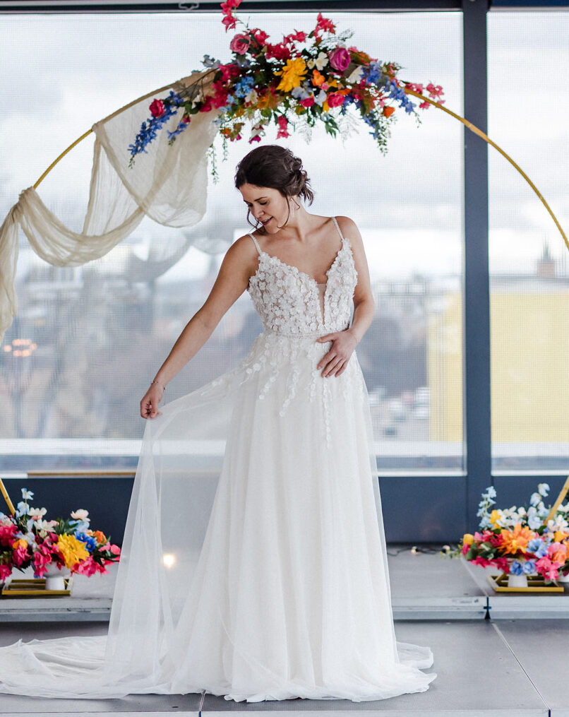 Braut schaut zur Seite, im Hintergrund ein Traubogen mit bunten Blumen - Hochzeitsfotografie Chemnitz