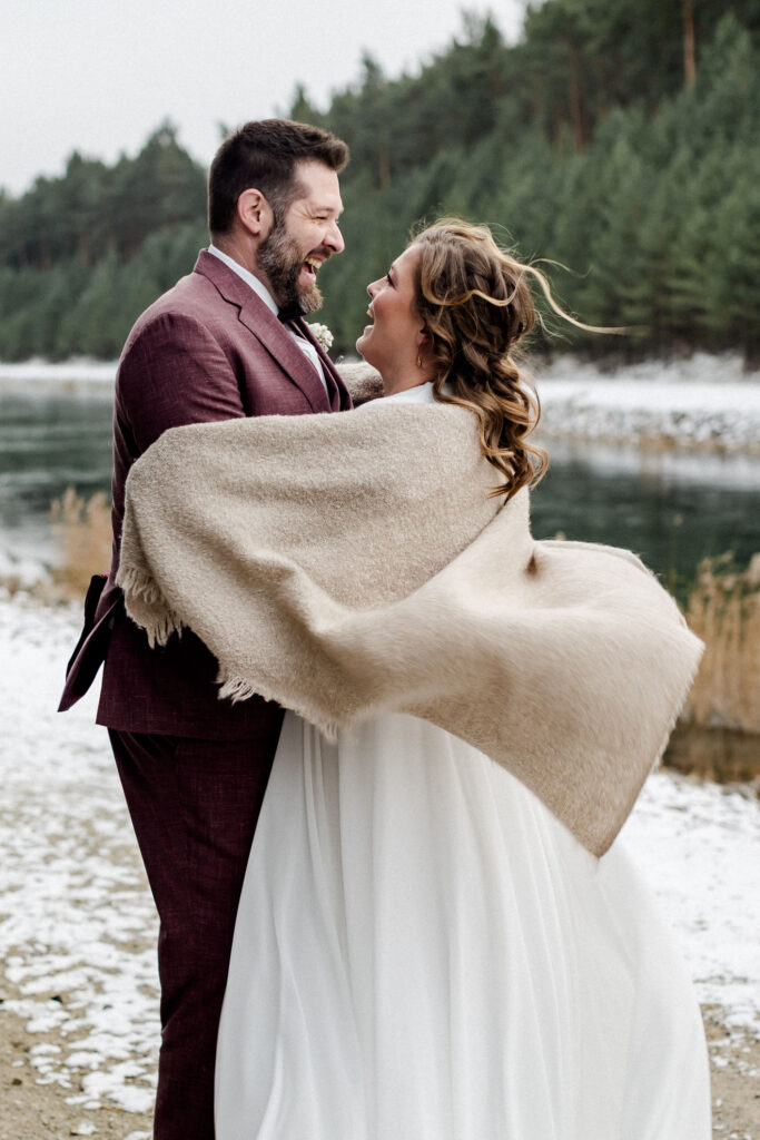 Braut und Bräutigam spazieren eng umschlungen im Schnee – winterliche Hochzeit für einen Hochzeitsfilm in Dresden